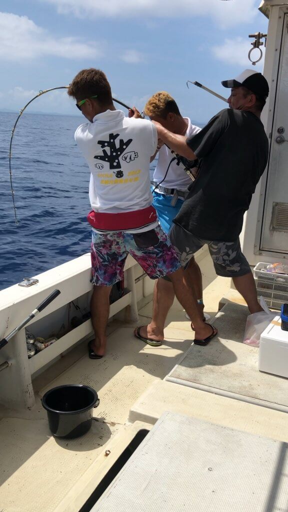 沖縄で大物が釣れて船長がサポートしている